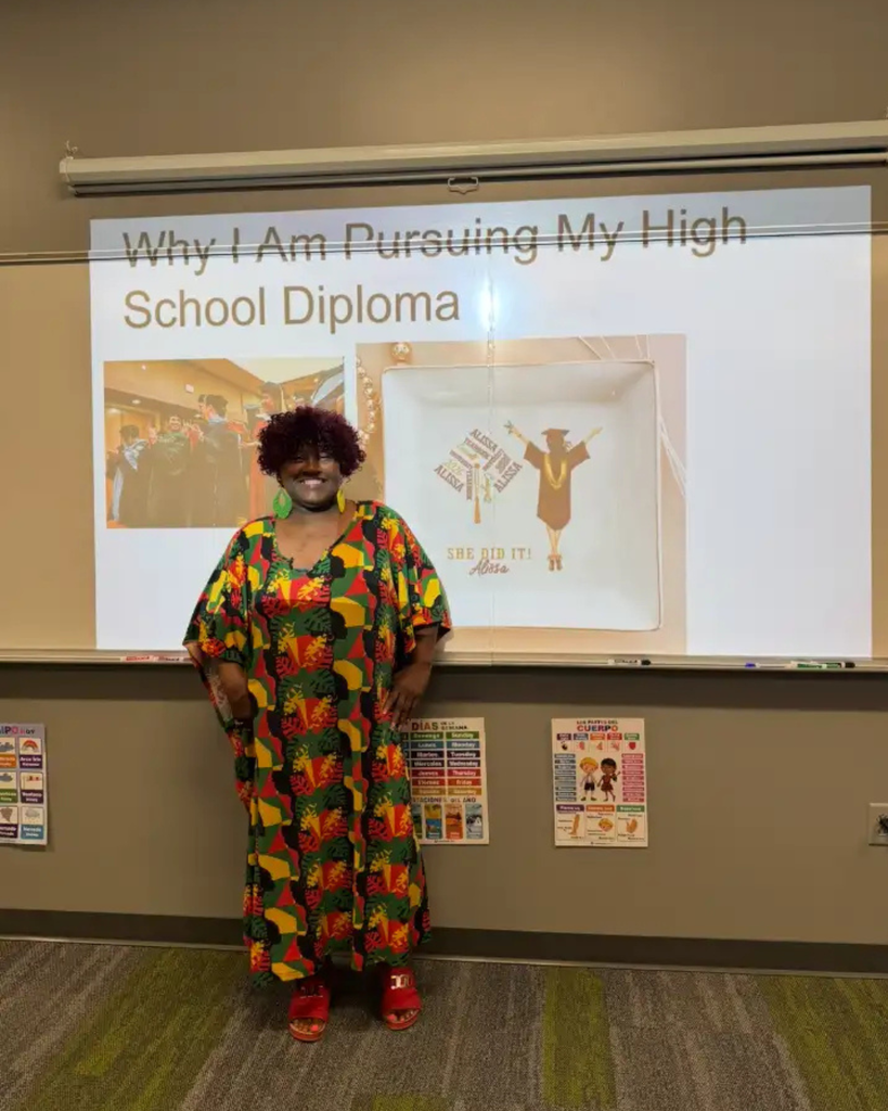 Student wearing traditional African cultural clothing and presenting why she is pursuing her diploma