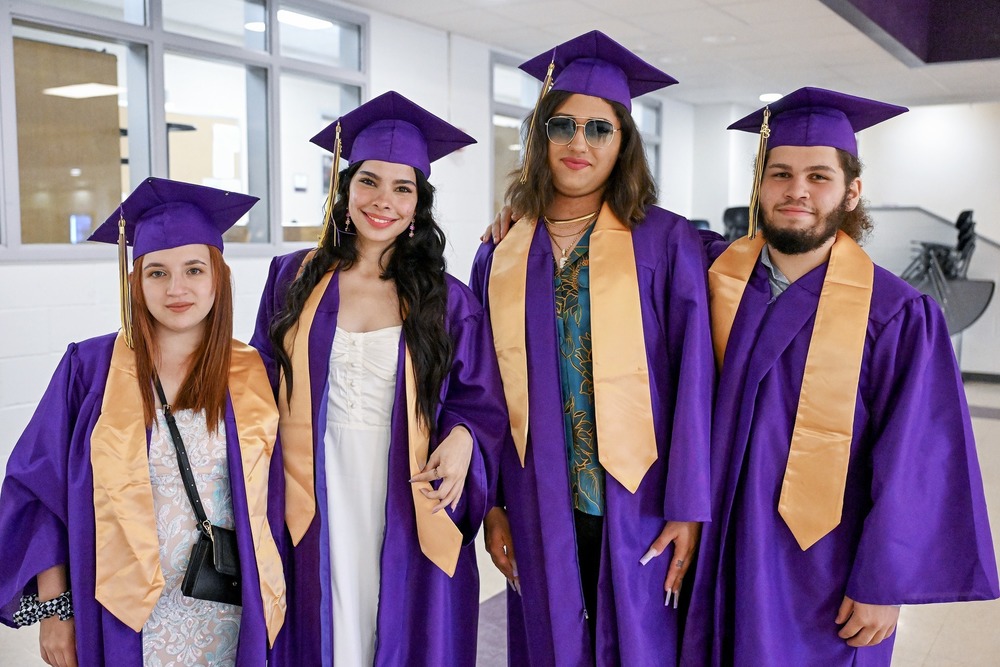 four graduates in caps and gowns