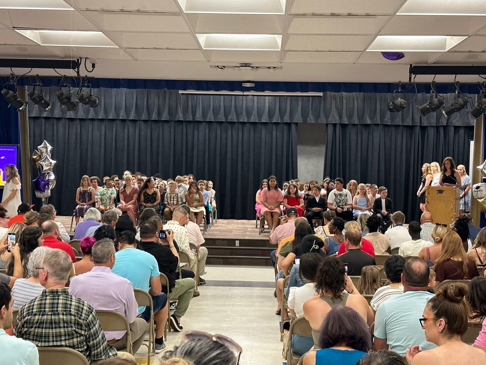 group of graduates on stage with large audience