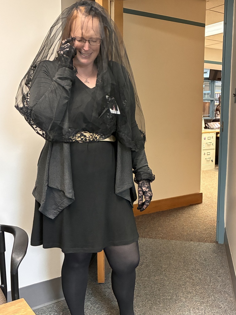 A teacher dressed in black with a veil and lace gloves “mourns” the passing of her fictional mentor as part of an immersive Junior High forensic science investigation scenario. The dramatic role-play helped students engage in storytelling, observation, and evidence analysis throughout the unit.