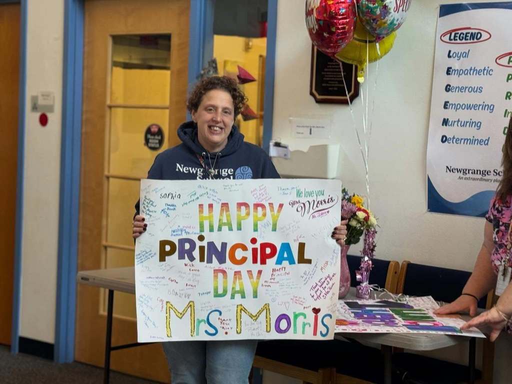Teacher holding a congratulatory sign