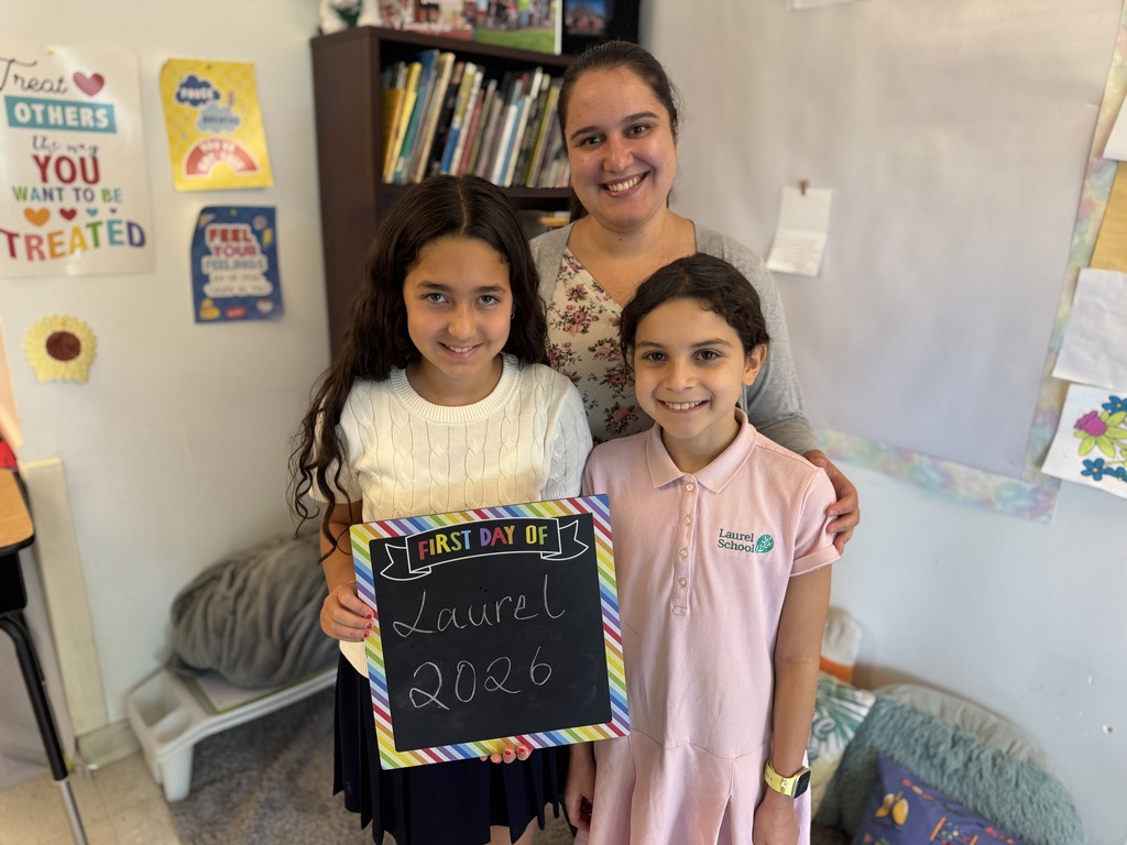Two children, one holding a chalkboard, smile. A woman stands behind them, arms around the shoulders of both.
