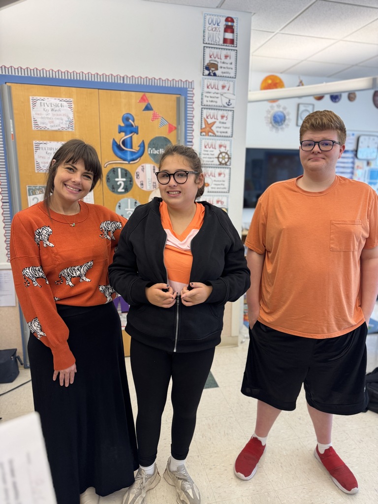 Three students stand together indoors; a woman with long hair, a girl with glasses, and a boy.