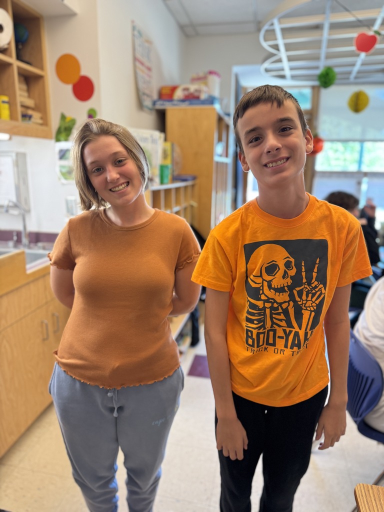Woman and boy stand next to each other in a classroom, smiling for a picture.