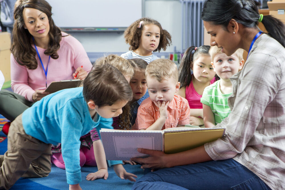 kids reading a book with teachers