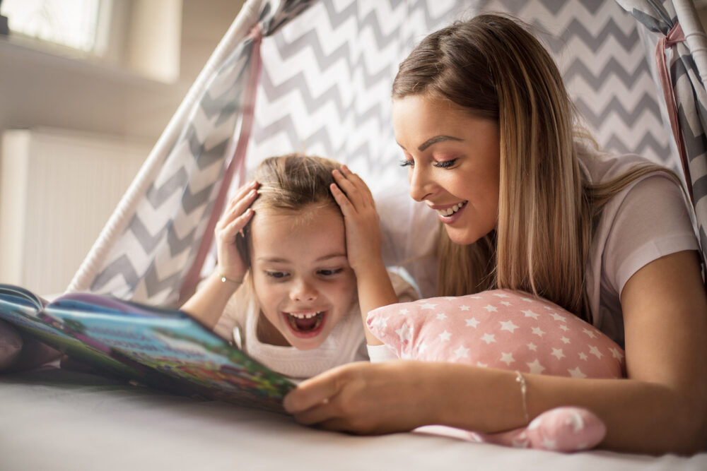 child and adult reading a book on the bed