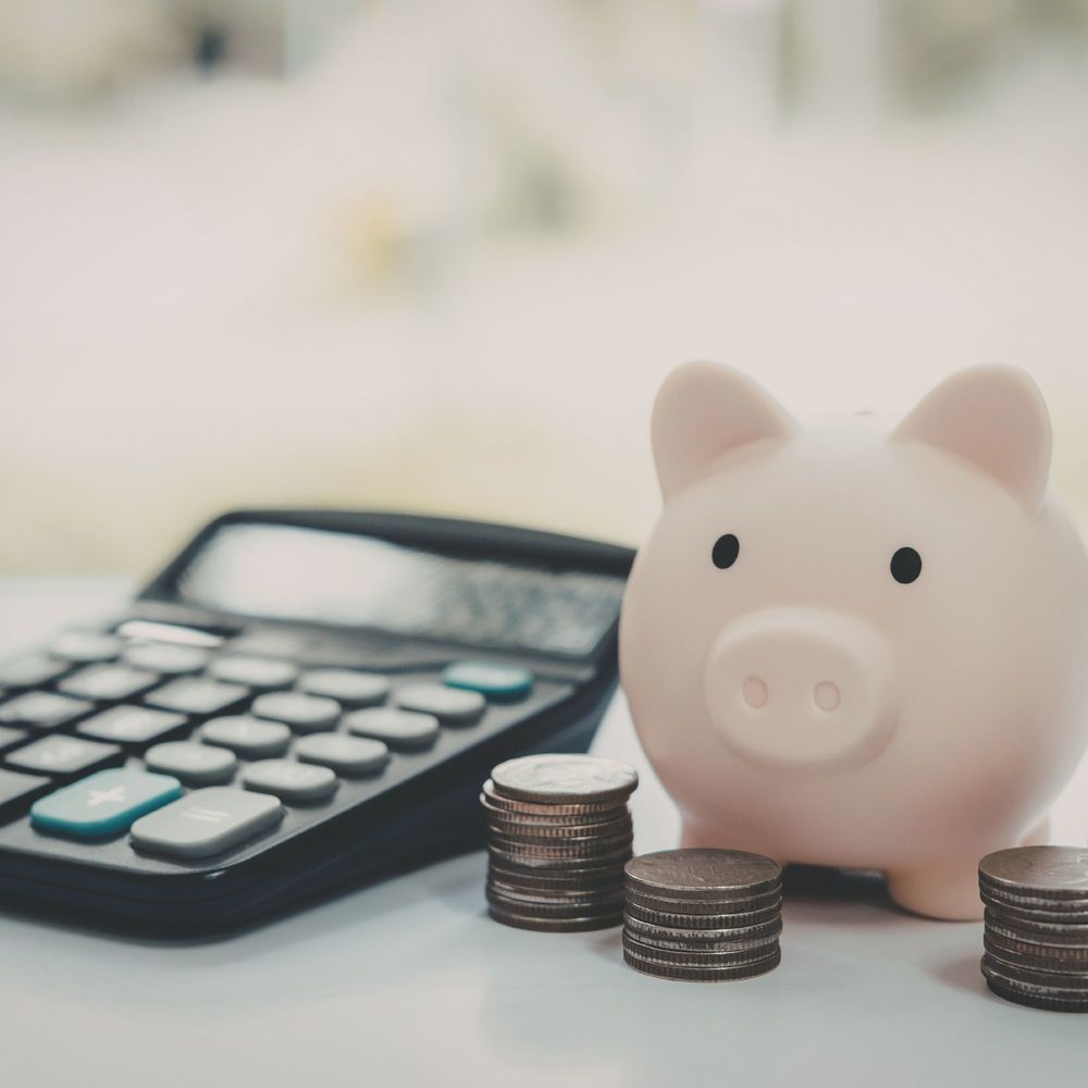 calculator, piggy bank and three stacks of coins