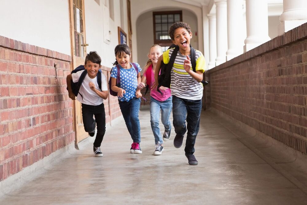4 kids running in school hallway