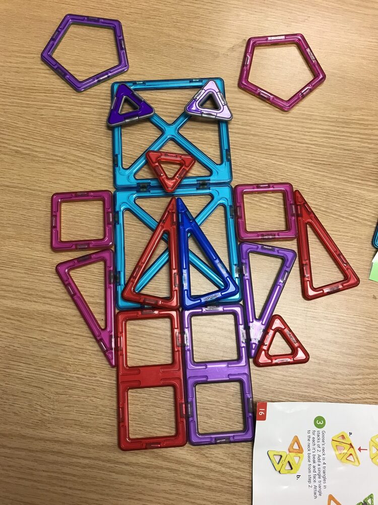 Colorful magnetic tiles arranged in the shape of an owl on a wooden desk.