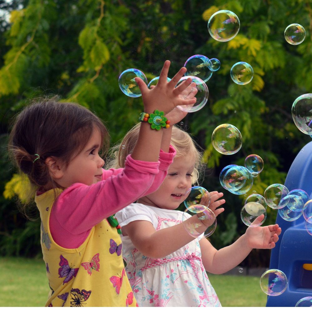 Two prek girls playing with bubbles outside