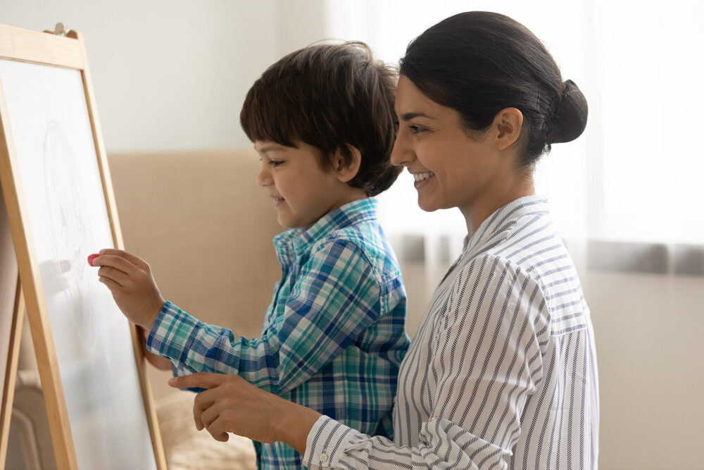 kid and adult drawing on chalkboard