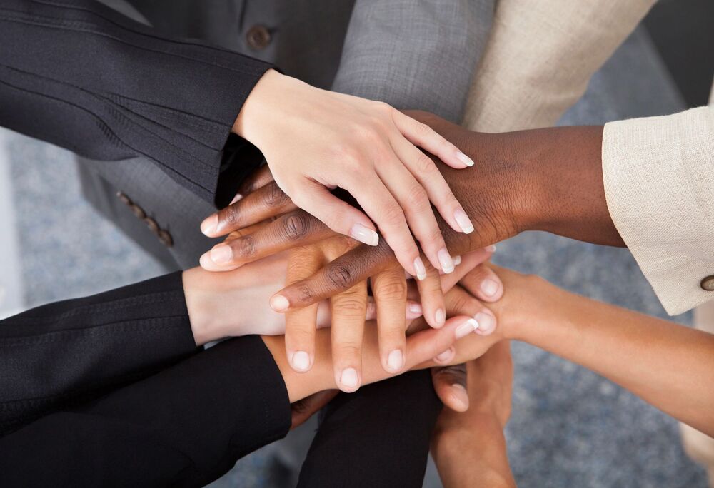 Diverse business team stacking hands together in unity and collaboration.
