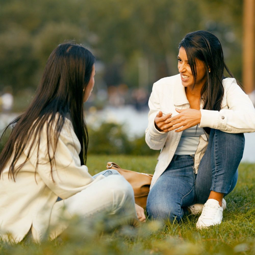 two women sitting on the ground, talking