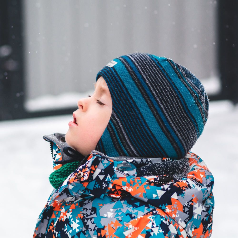 prek child outside during winter with head tilted up and eye closed