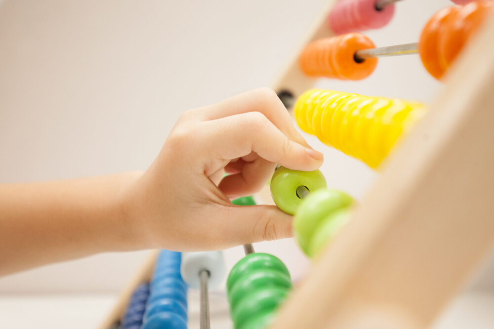 close up of childs hand playing with multicolor bead game