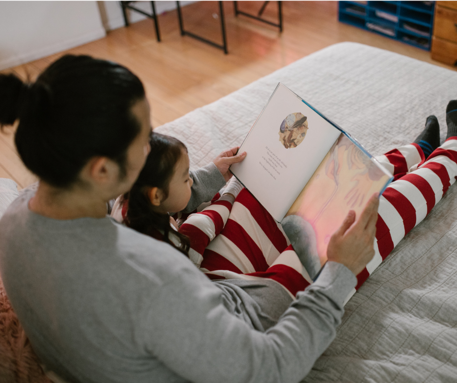Young child sitting on adults lap reading book