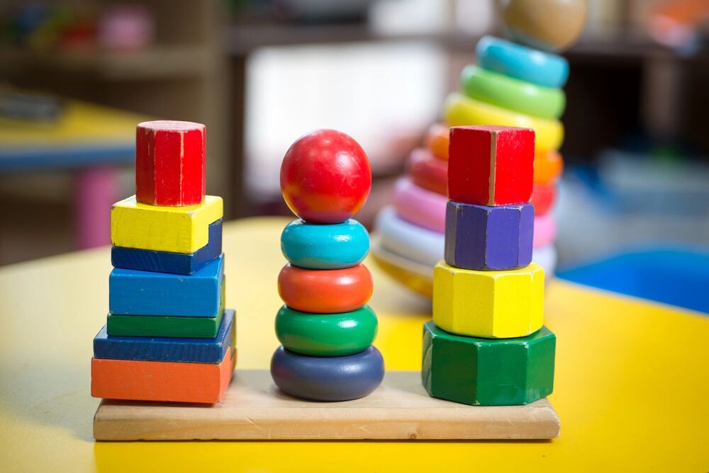 Colorful wooden stacking toy featuring rings, blocks, and geometric shapes.