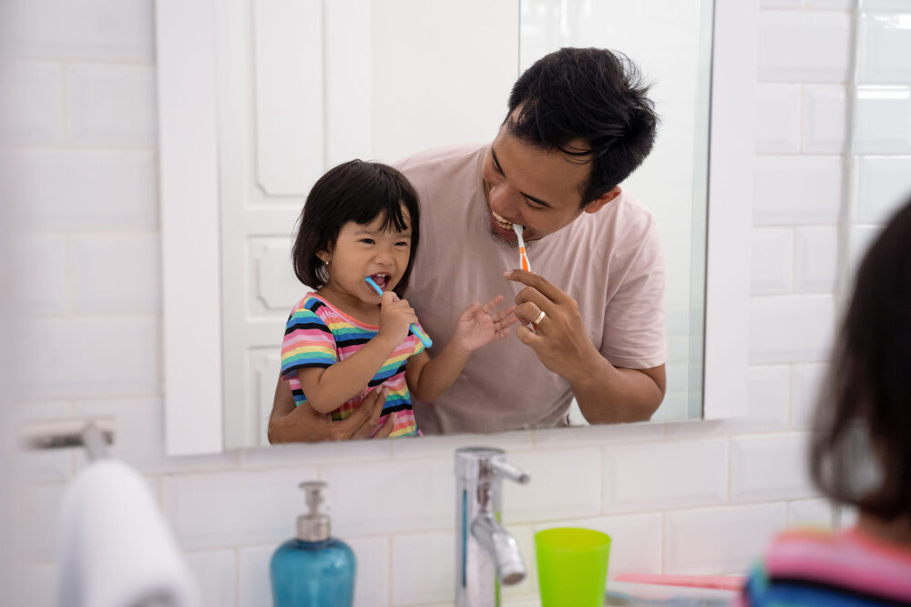 parent helping kid brush their teeth