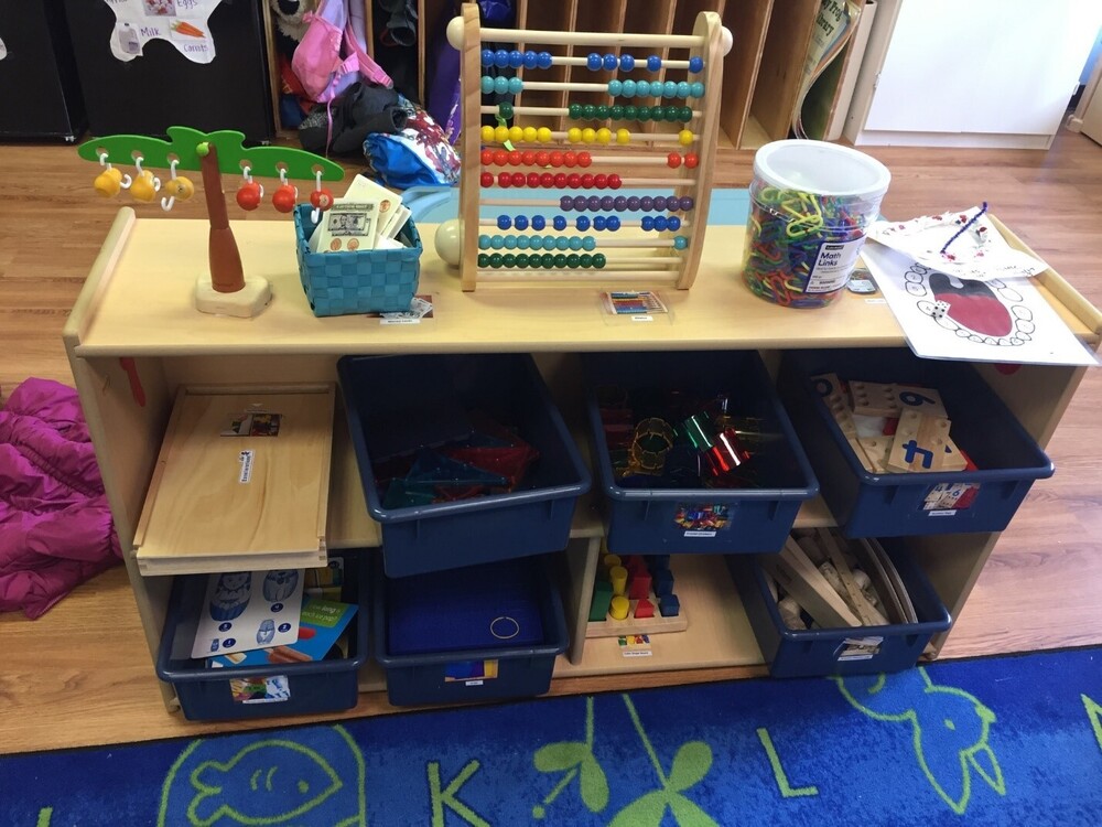 A classroom shelf organized with math toys, an abacus, and counting manipulatives for kids.
