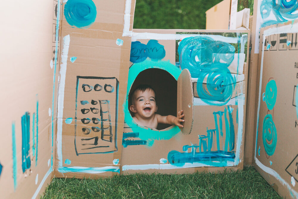 kid playing with handpainted cardboard boxes
