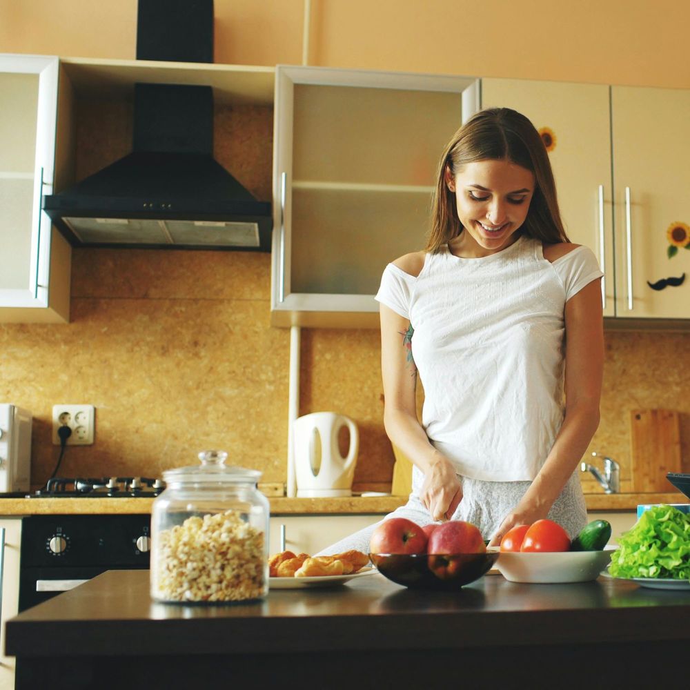 woman in kitchen, with food on counter, preparing a meal