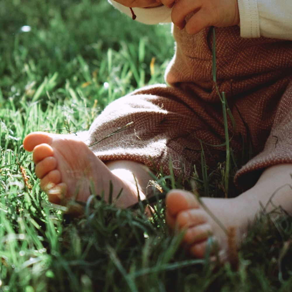 Child sitting in grass with bare feet