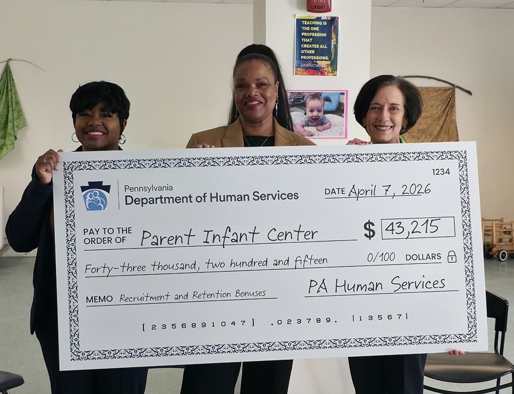 Three women hold a large check from the Pennsylvania Department of Human Services, displaying the amount of $43,215.