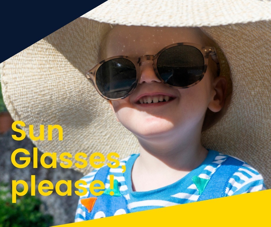Child wearing a hat and sunglasses smiles, with overlayed text "Sun Glasses please!" on yellow background.
