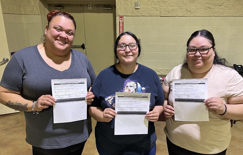 three students posing for the camera with certifications