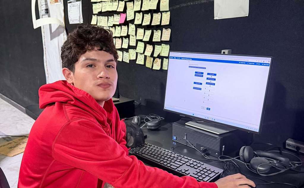 student facing camera at a computer workstation