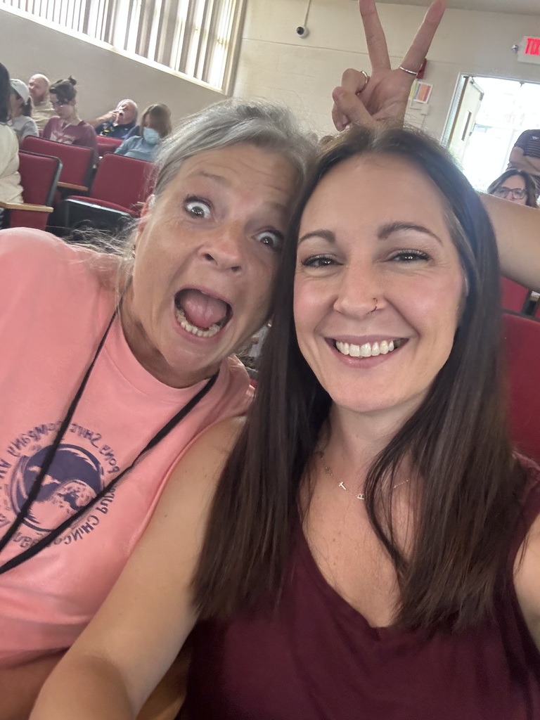 two women posing for the camera. one is making an excited face with her mouth wide open and the other is smiling