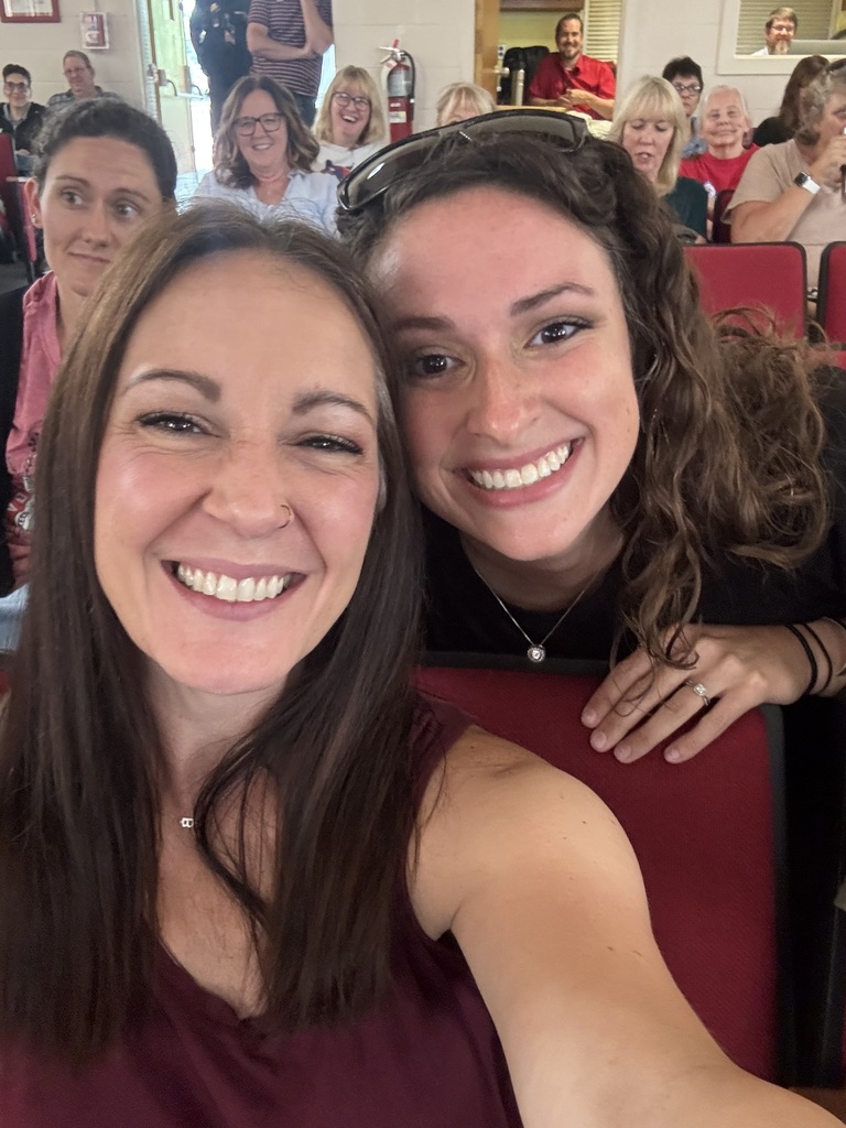 two women smiling for the camera in the VSDB auditorium. several people are in the background also smiling