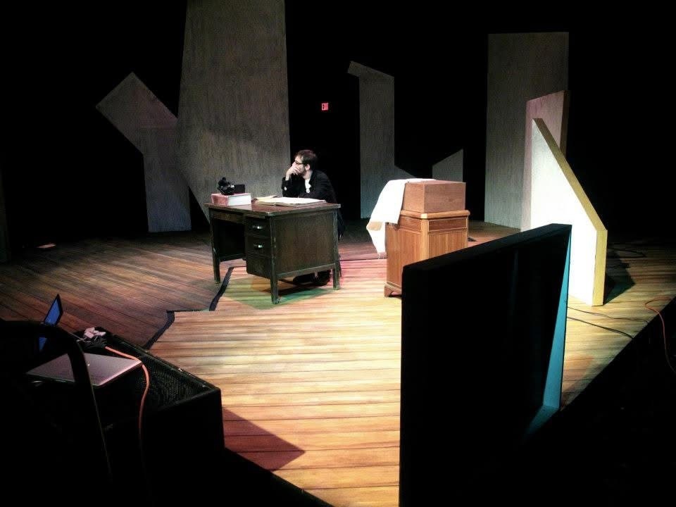 Neil on stage sitting behind a desk.