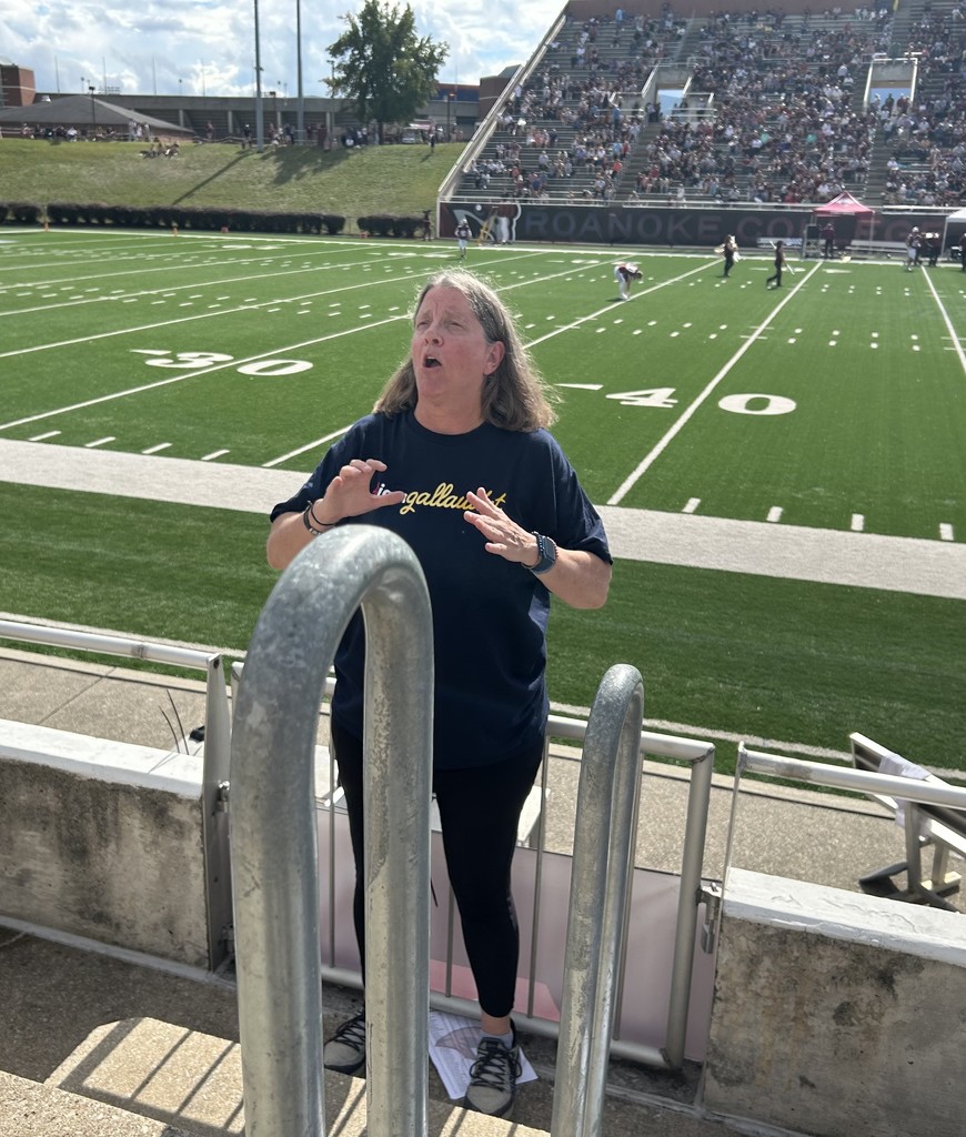 Daphne Cox is welcoming everyone while standing in front of the football field.