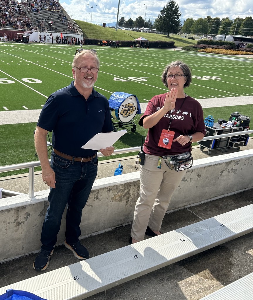 Senator Crhis Head is standing next to an interpreter in front of the football field and is reading off a script.