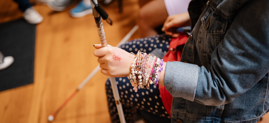 closeup image of female student with a fake wound on her hand. she is holding her cane.