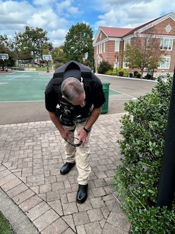 A VSDB Security Officer is looking under some bushes