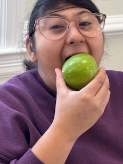a student looks at the camera while biting into a green apple