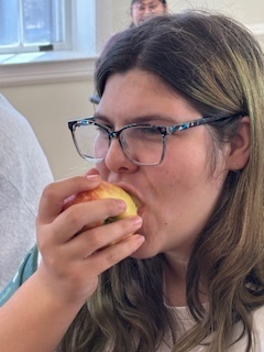 A female student is biting into a yellow nad red apple