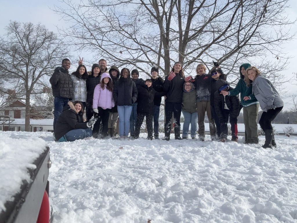 kids are lined up smiling with some staff outside in the snow
