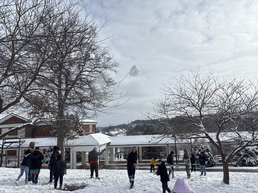 kids are playing in the snow, and a sowball is being hurled at the camera
