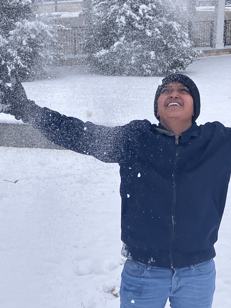 A student is smiling while throwing snow in the air 