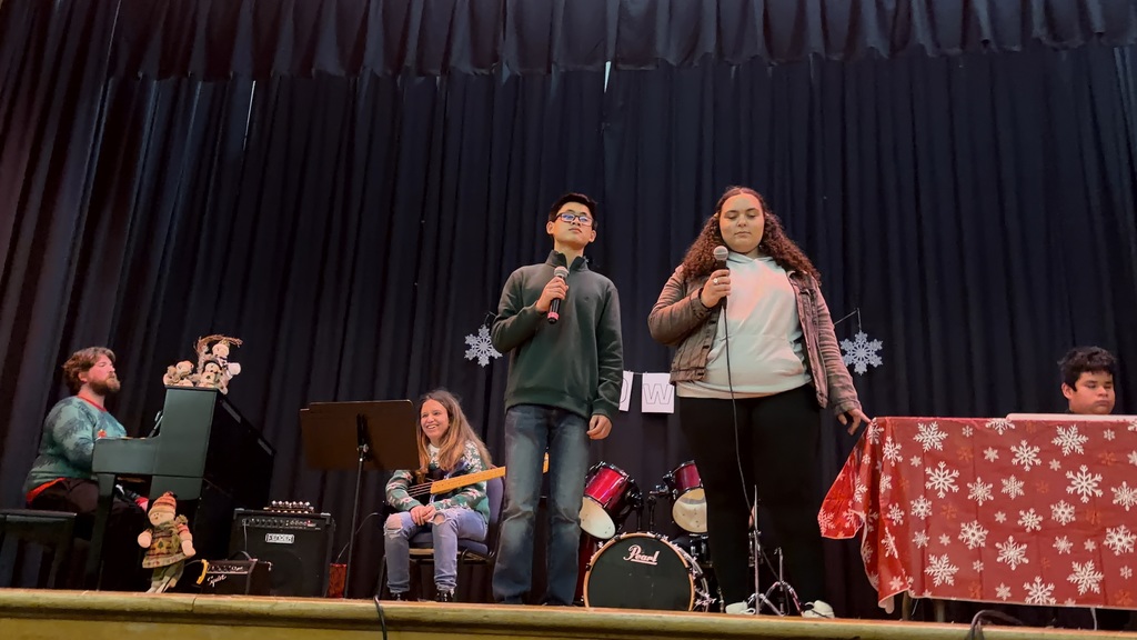 Two students sing on stange, a band is behind them