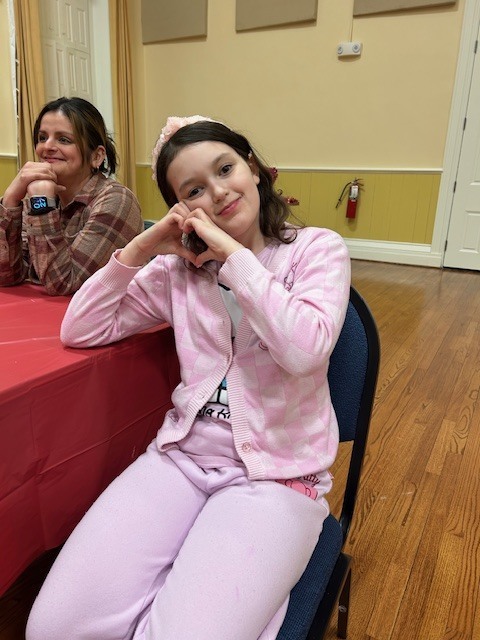 girl dressed in pink and holding her hands in the shape of a heart