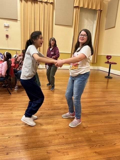 two girls holding hands and dancing