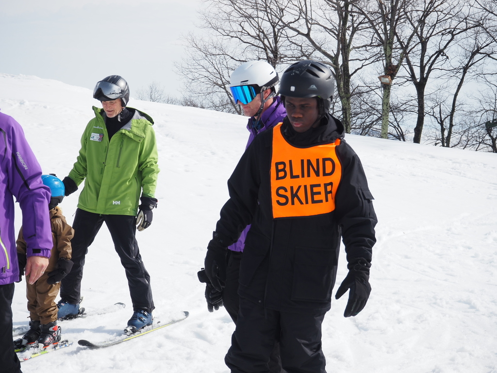 A blind skier is walking in the snow.