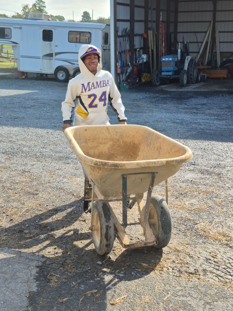 A student is moving a wheelbarrow outside. 