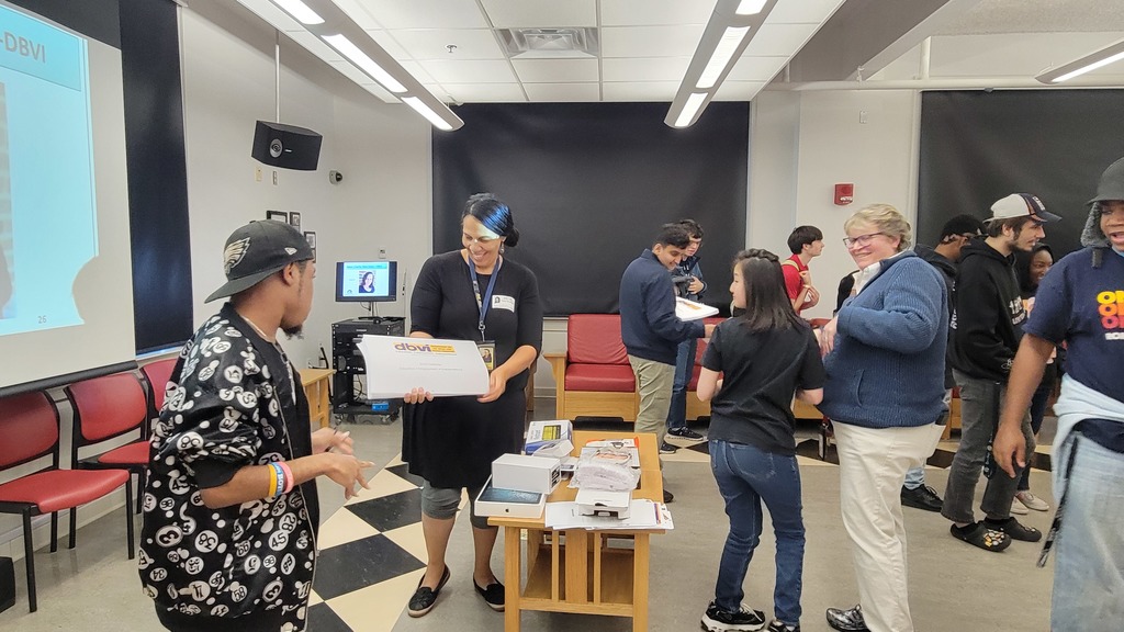 students mingle in a room while a power point slide is projected.