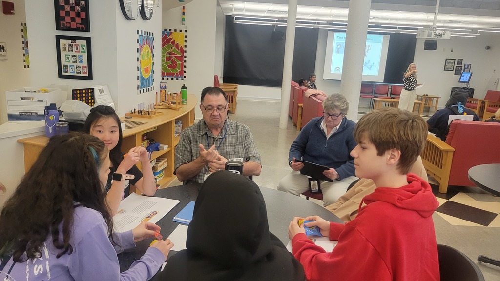 students are sitting around a table while having a conversation