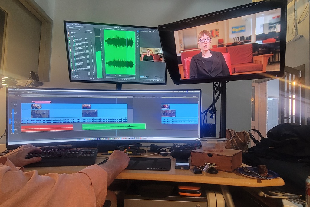 Three monitors are set up. Two dispaly editing software, one has a clip of the film on it.